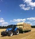 Traktor New Holland T5 s plně naloženým vozem Pronar při svozu slámy